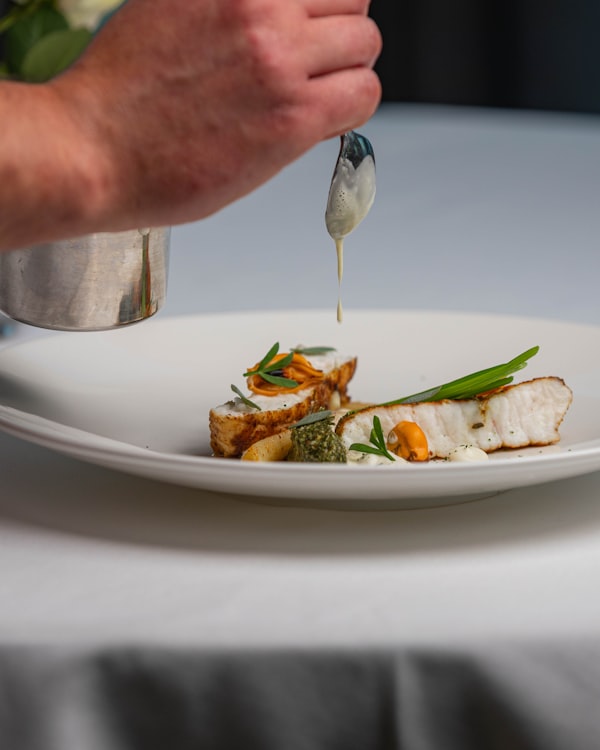 Fischgericht mit Gemüse auf weißem Teller