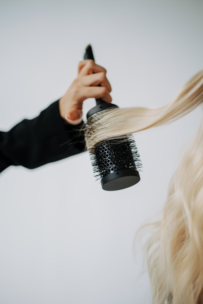 Stylistin föhnt Haare eines Kunden